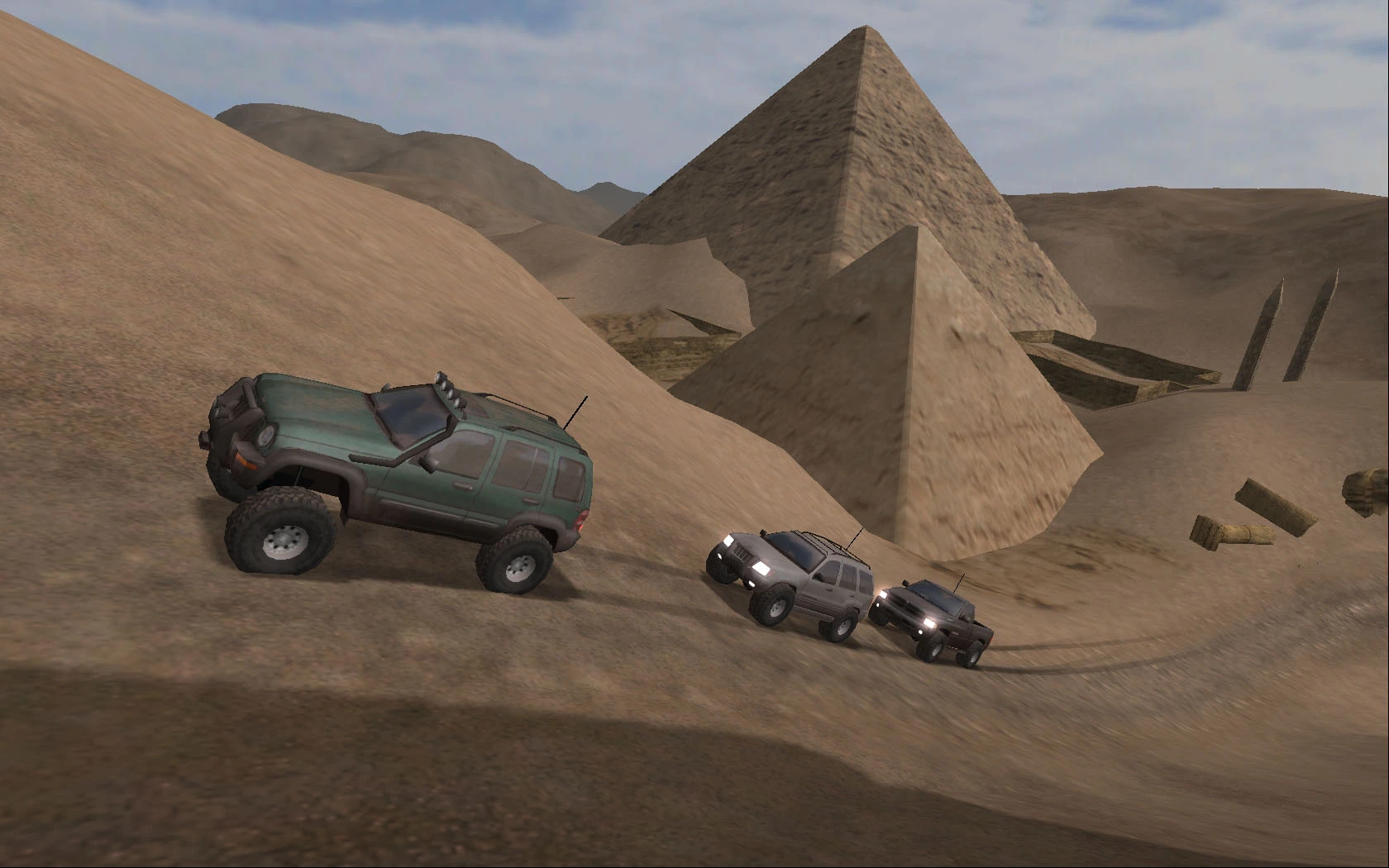 Mehrere SUVs fahren durch die Wüste mit Pyramiden im Hintergrund