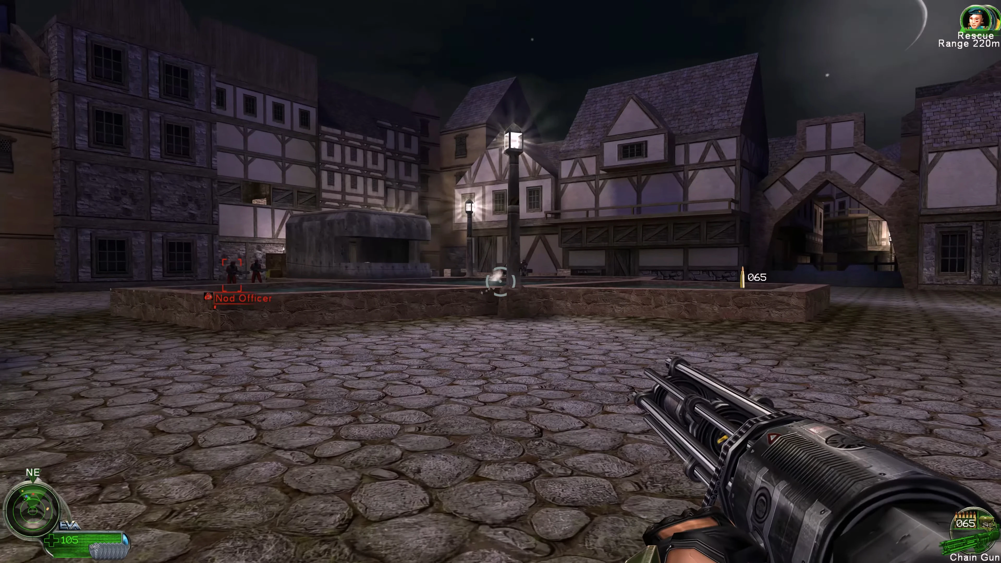 Нічний міський краєвид у Command & Conquer Renegade з бруківкою та освітленими середньовічними будівлями, HUD зброї в кадрі