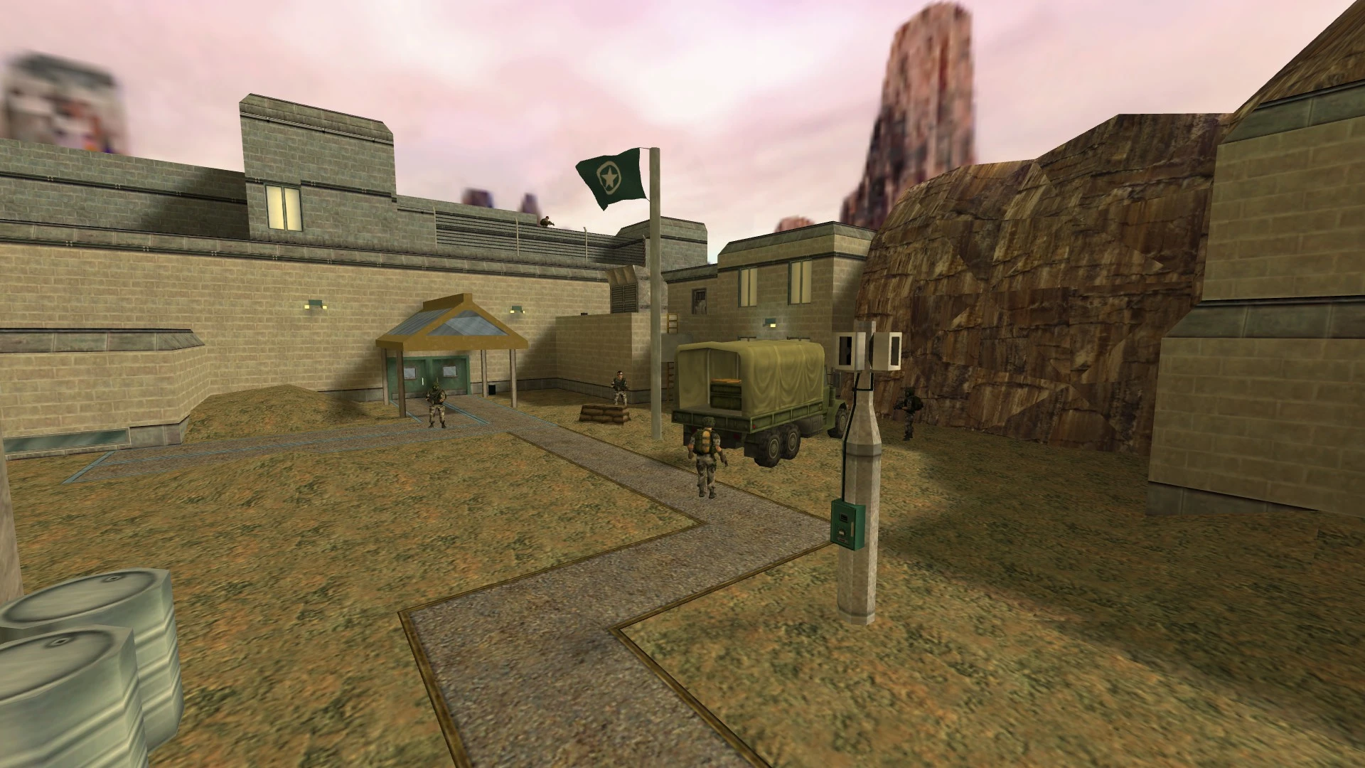 Außenansicht eines militärischen Hofs mit getarnten Soldaten, einem Lastwagen, Steingebäuden und Fahnenmast