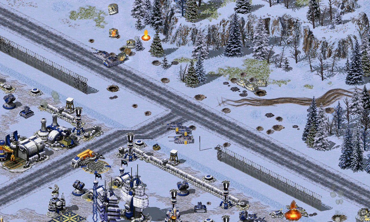Campo de batalla cubierto de nieve con tanques intercambiando fuego y explosiones cerca de una base fortificada en mod de Red Alert 2