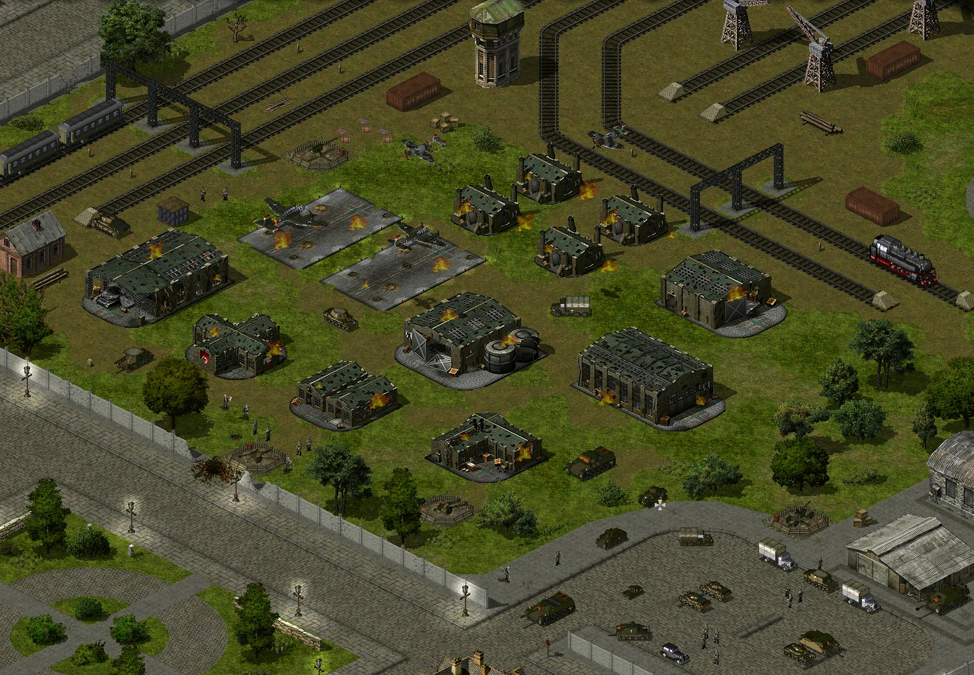 Draufsicht auf eine kriegsgeschädigte Militärbasis mit beschädigten Gebäuden, Panzern und Zügen auf Gleisen im Yuri's Revenge Mod D-day
