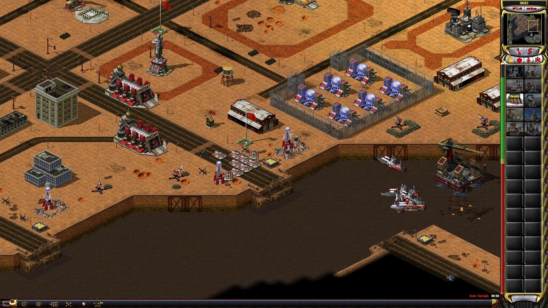 Captura del juego con base en el desierto, tanques soviéticos, infantería, estructuras y unidades navales defendiendo la costa en el mod Yuri's Revenge