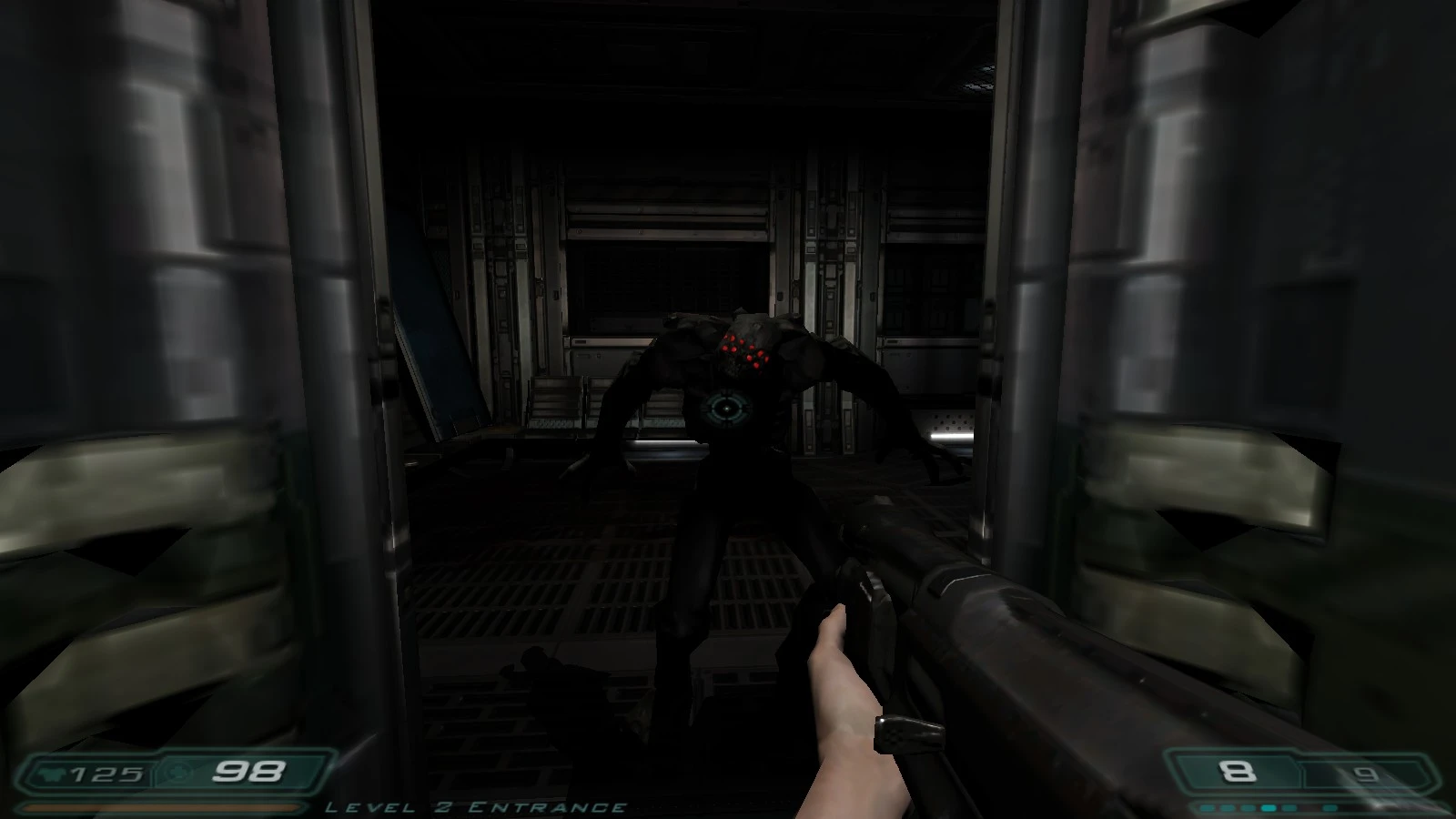 Vista en primera persona disparando a un demonio con múltiples ojos rojos en un pasillo industrial oscuro en Doom 3 Enhanced Edition