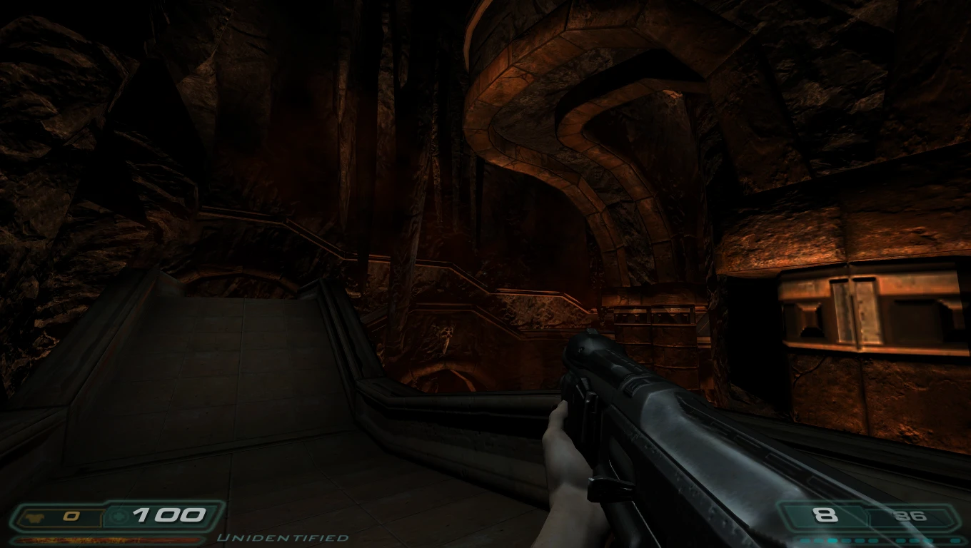 Vista en primera persona sosteniendo un rifle de asalto dentro de una caverna oscura de roca con estructuras metálicas en el mod Doom 3 The Lost Mission
