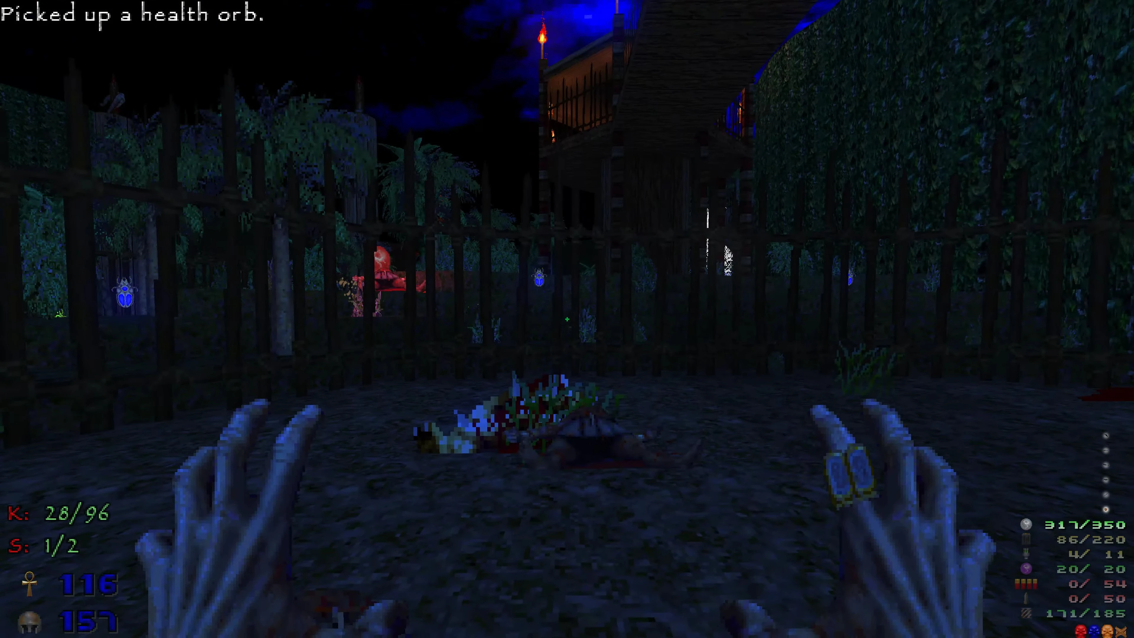 Player hands with ammo HUD in dark area behind metal fence with blue glowing scarabs and torches
