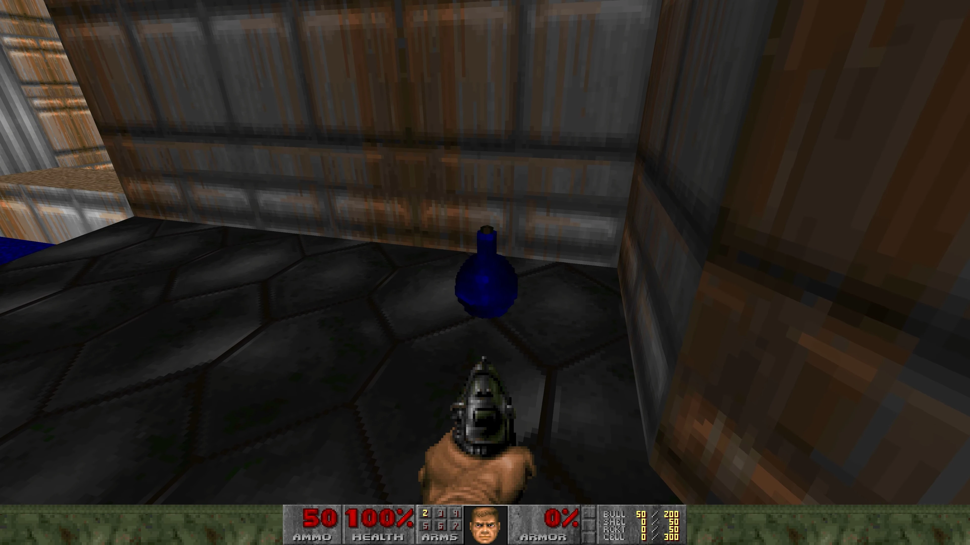 First-person view showing a pistol and a blue ammo pickup in a corner with hexagonal floor tiles and metal walls