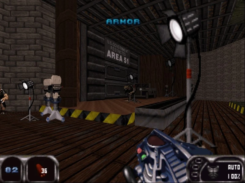 Erste-Person-Sicht auf hölzernen Innenraum mit Scheinwerfern, Area 51 Schild, Gegnern und Waffe im Duke Nukem 64 Mod