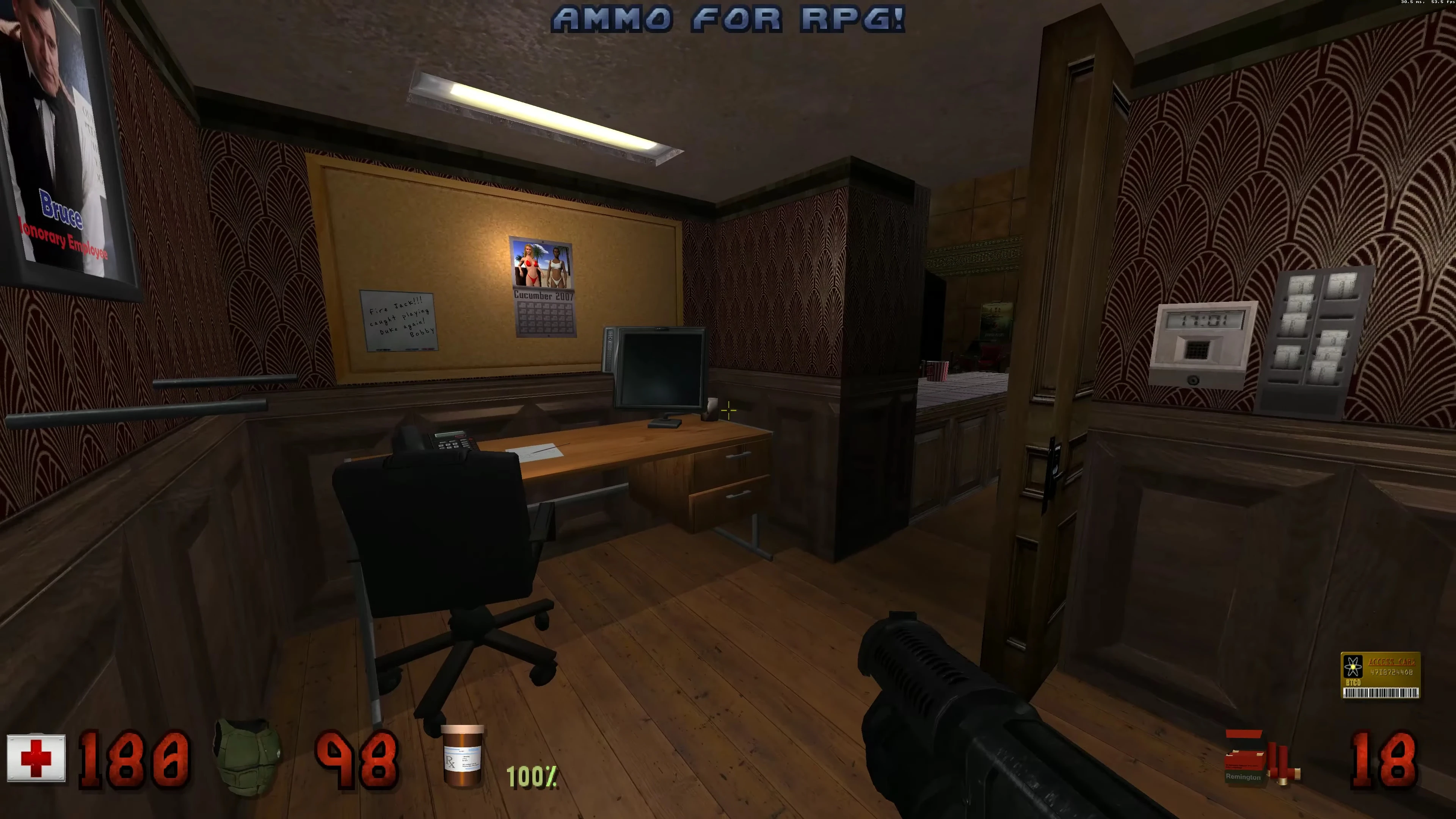 Ansicht eines Büroraums mit Schreibtisch, Computermonitor, Stuhl und Wandpostern im Duke Nukem 3D Mod