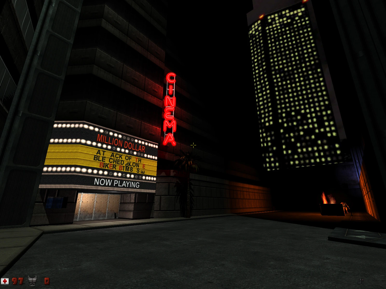 Zrzut ekranu ukazujący ciemną miejską ulicę z oświetlonym szyldem kina i światłami okien drapacza chmur w Duke Nukem 3D
