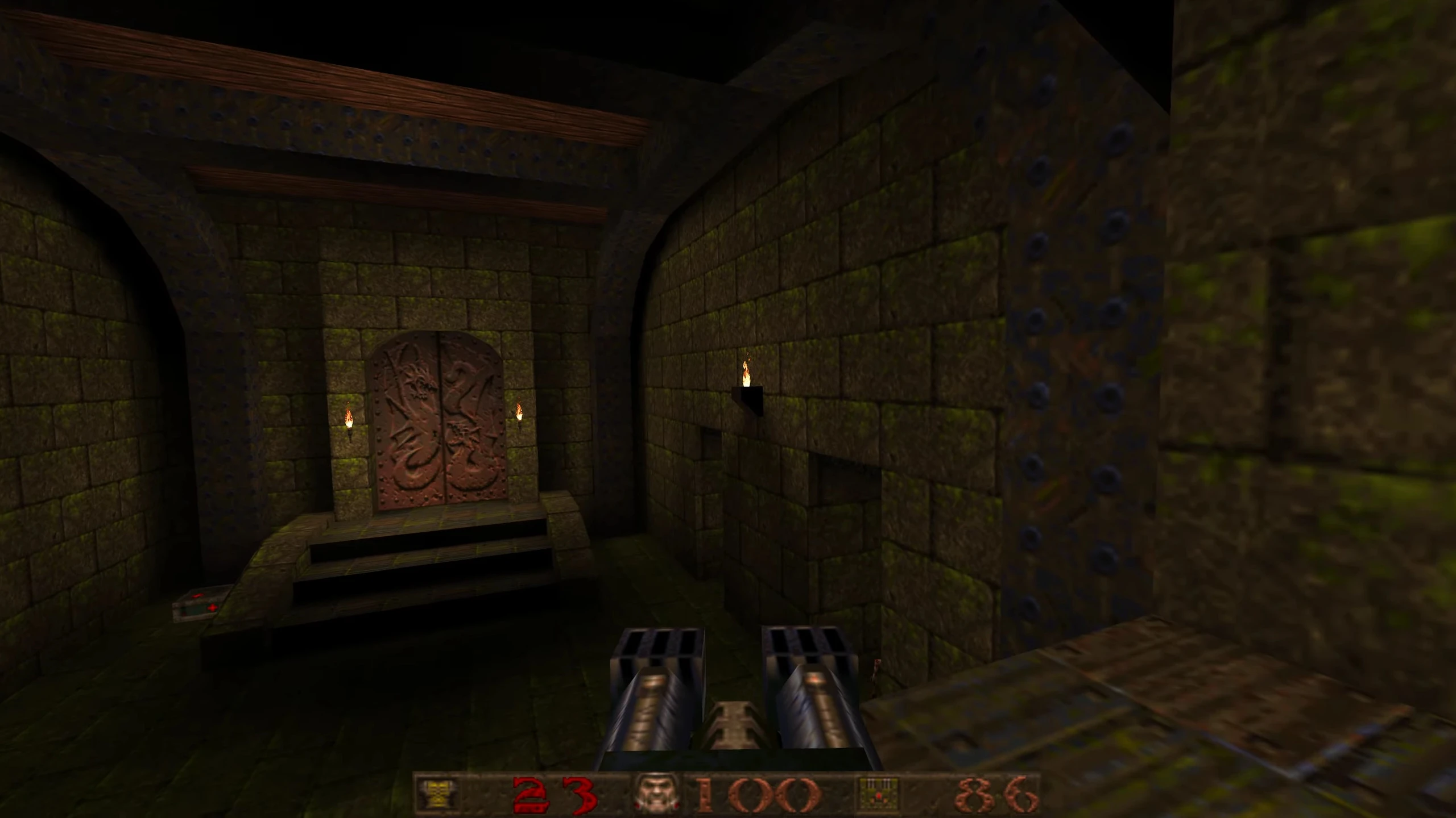 First-person view of a dimly lit stone corridor with double dragon-engraved doors and dual barrels in Quake