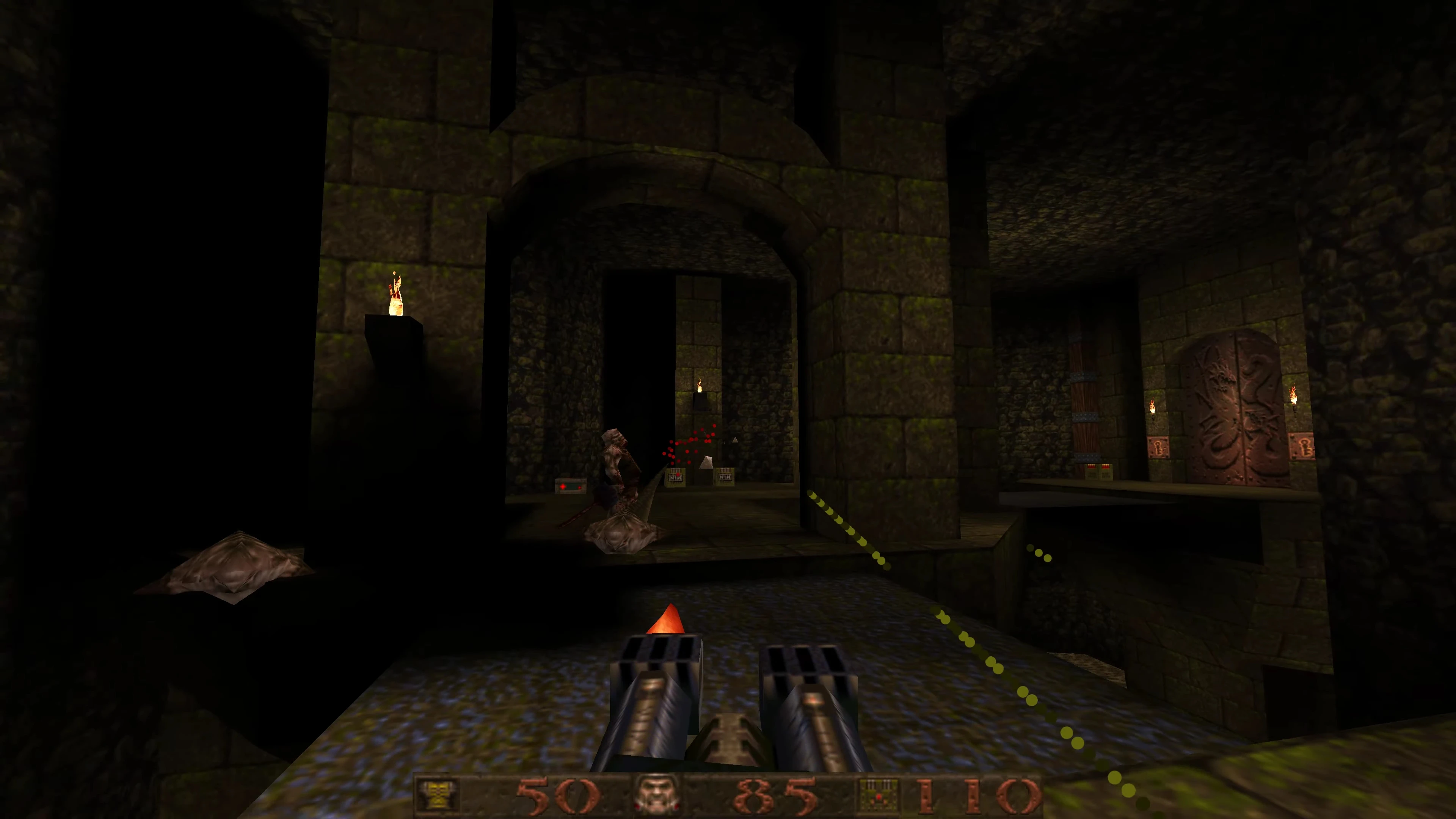 First-person view of Quake gameplay with double-barreled gun in a dark fortress hallway shooting an enemy
