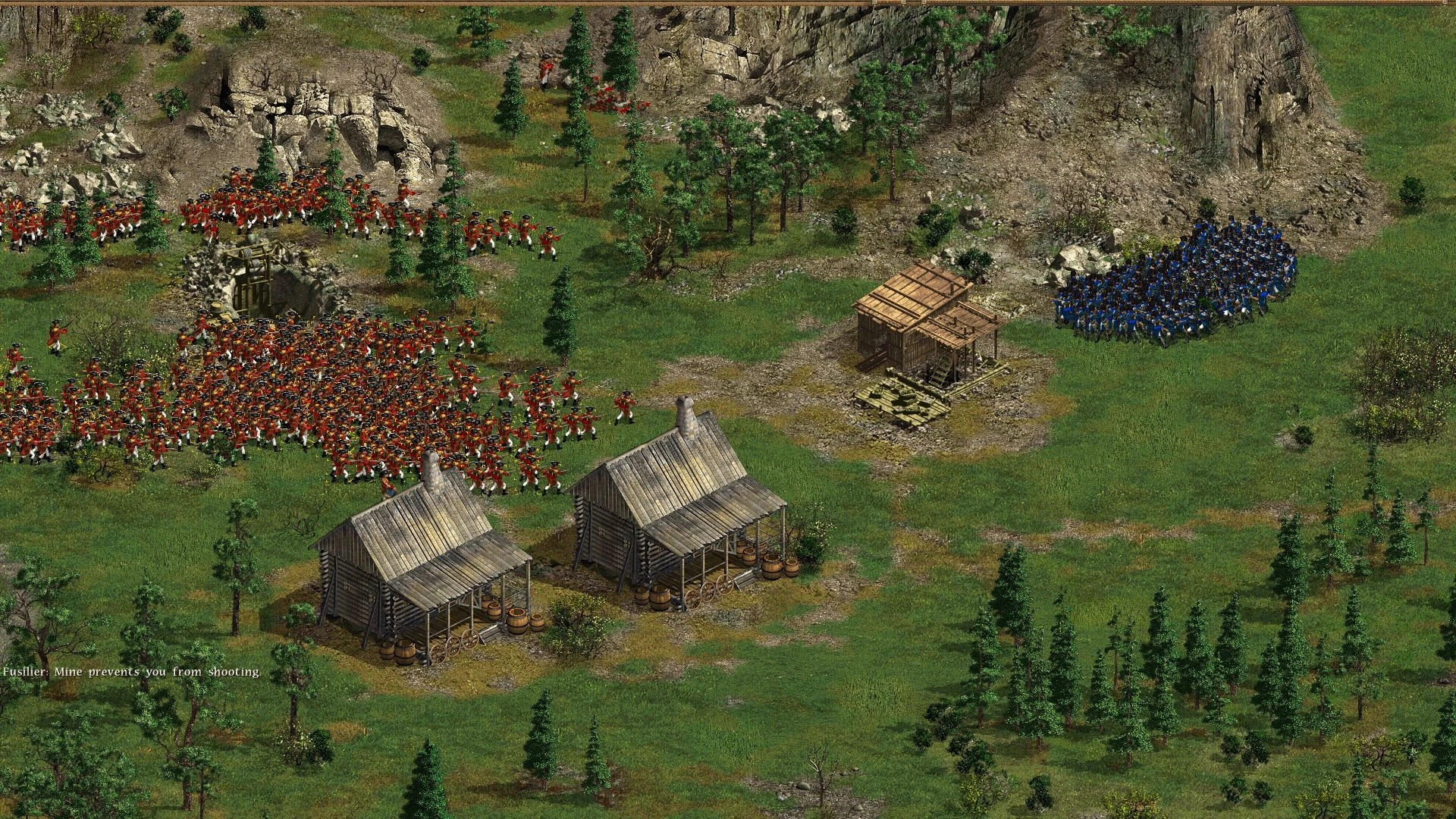 Soldados rojos y azules posicionados cerca de cabañas de madera y terreno rocoso en una escena de batalla de American Conquest
