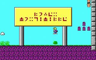 Personaje verde flotando junto a cartel amarillo con símbolos alienígenas y plataformas rosas en Commander Keen