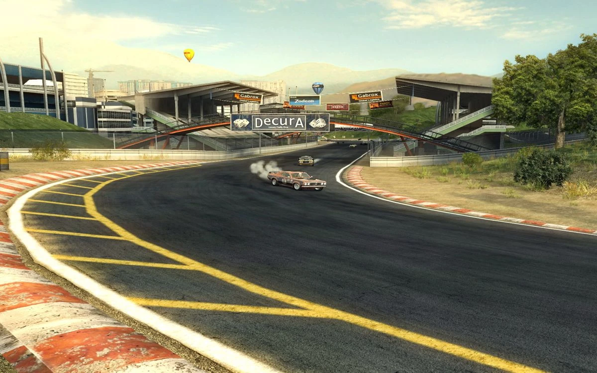 FlatOut 2 screenshot: racing cars drifting on a wide turn near the stadium complex