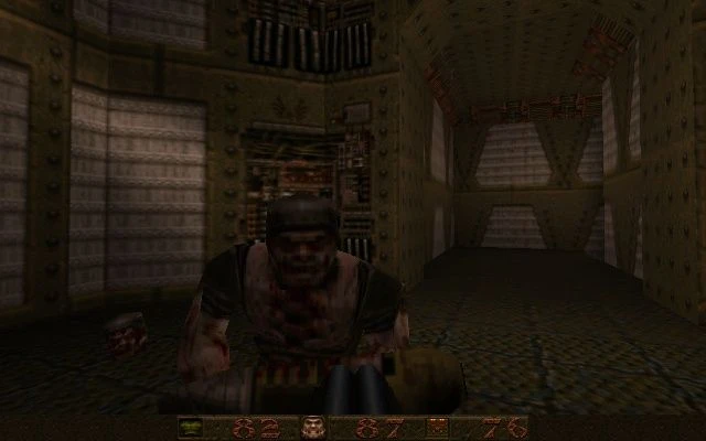 Enemigo atacando al jugador en un pasillo industrial con poca luz en Quake 1996 con HUD de salud y munición