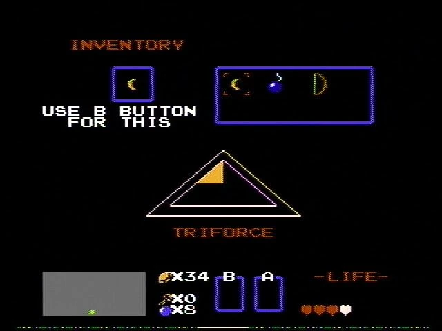 Pantalla de inventario de The Legend of Zelda 1987 con símbolo Trifuerza, bomba y selección de objeto