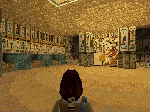 Personaje del jugador frente a una pared decorada con jeroglíficos egipcios y una estatua sentada dentro de una tumba antigua en Tomb Raider 1996