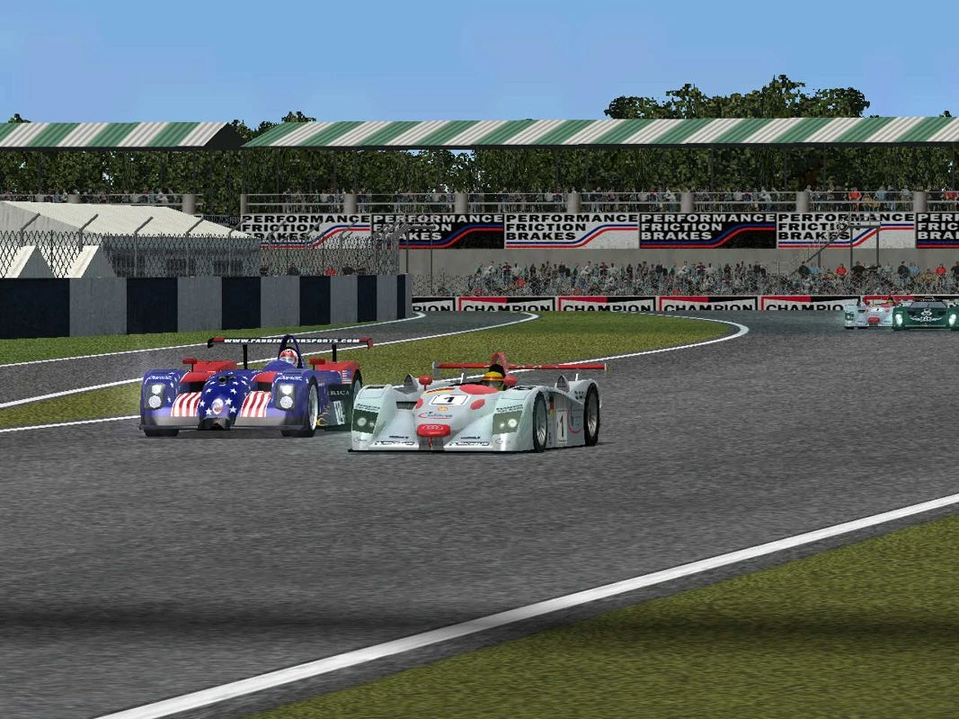 Der silberne Audi R8 LMP fährt vor einem Panoz-Prototyp mit US-Flaggenlackierung in einer Kurve der Strecke in Total Immersion Racing.