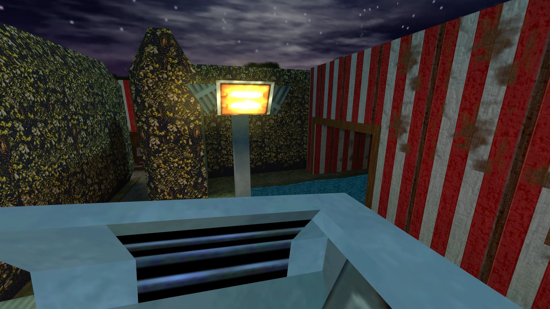 Vista de laberinto de setos, poste de luz brillante y paredes a rayas rojas y blancas bajo cielo nocturno nublado en mod de Half-Life