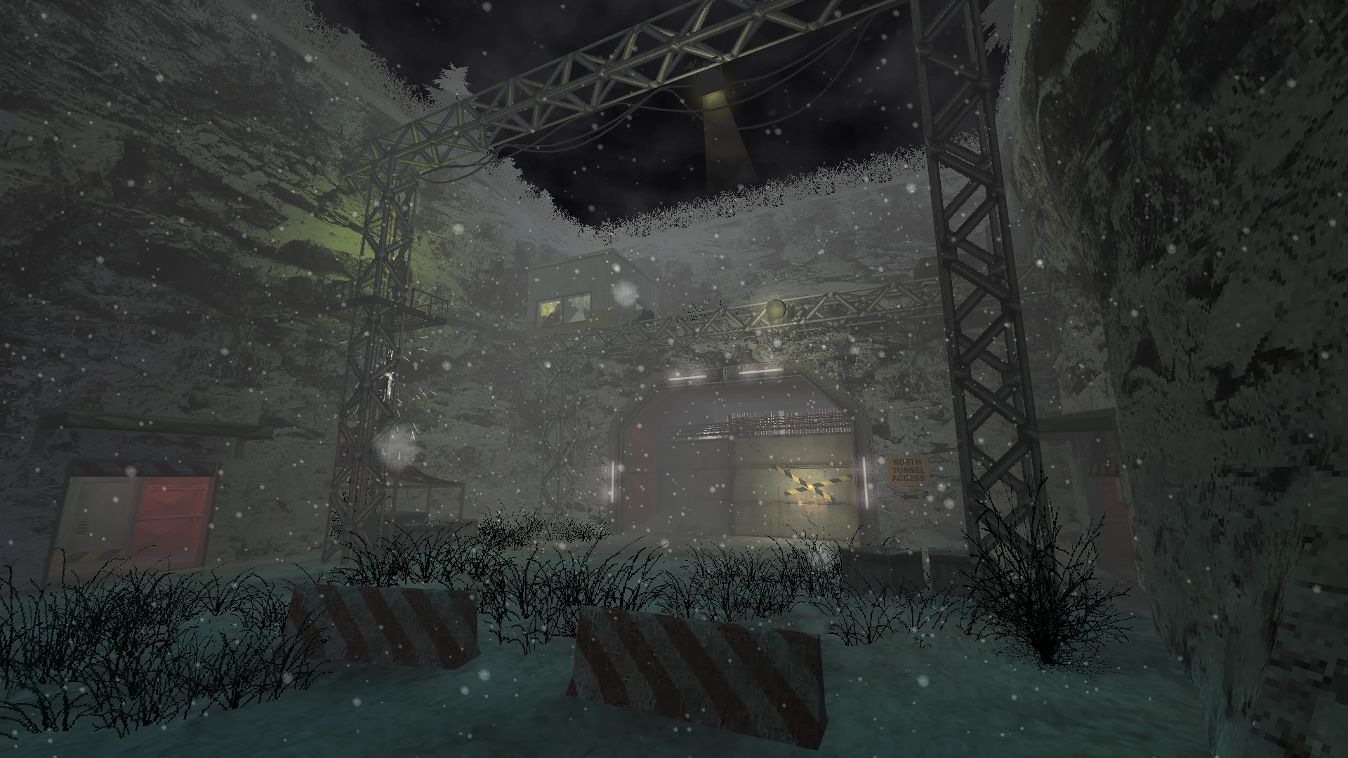 Snow falling around a metal framework structure and a tunnel entrance with a guard post and signs