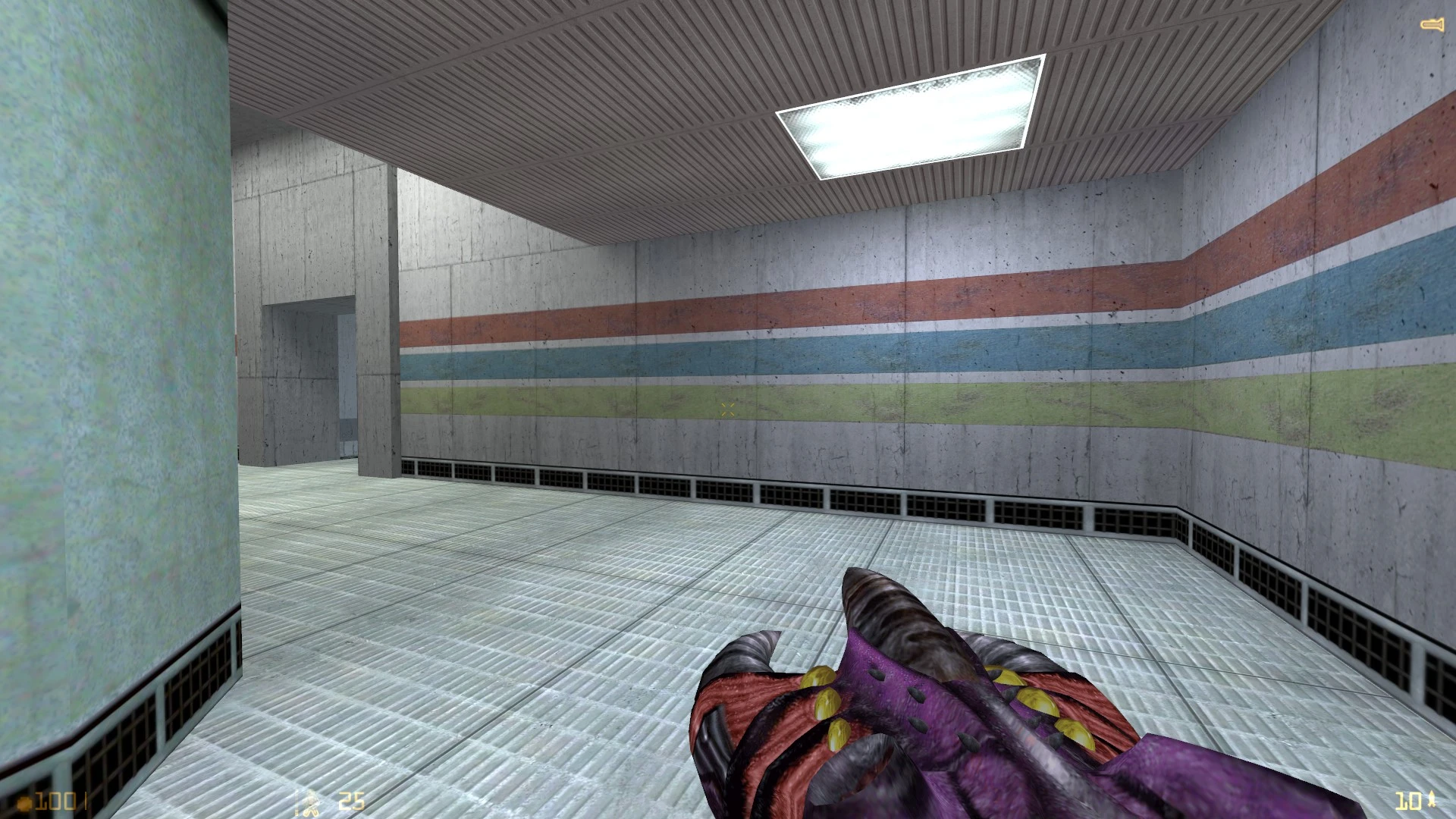 First-person view of a sterile interior room with colored stripes on concrete walls and an alien claw weapon visible