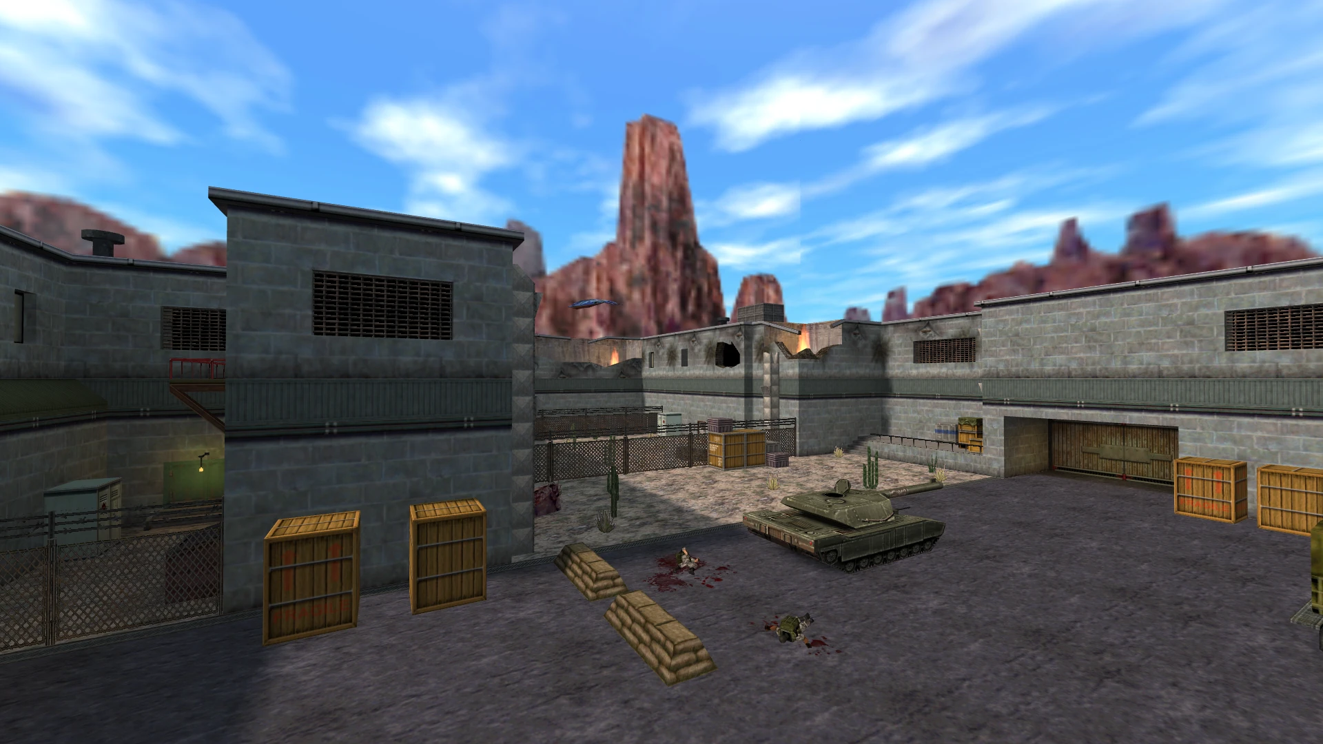 Blick auf den Hof einer Militärbasis mit Kisten, einem Panzer und umliegenden Wüstenbergen im Mod Half-Life: Insecure