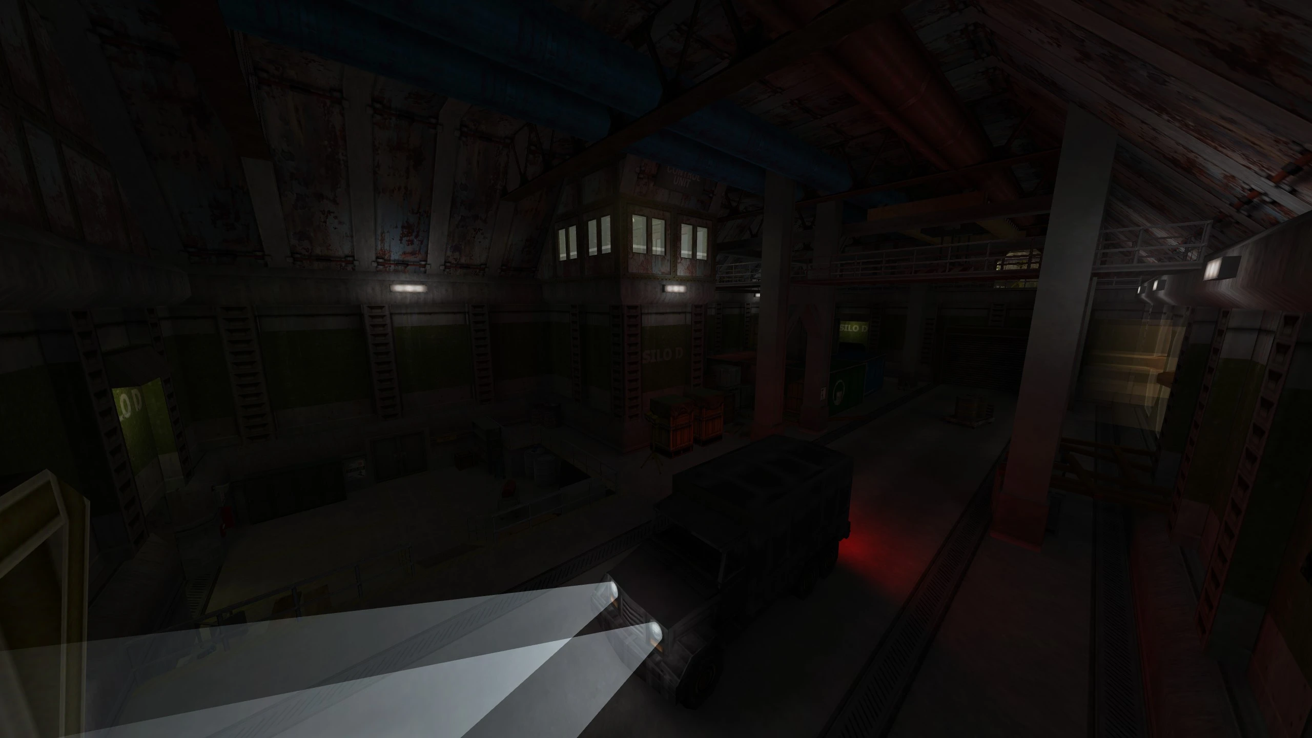 Dimly lit industrial warehouse interior with trucks, walkways, and control rooms in Half Life NO - HOPE mod
