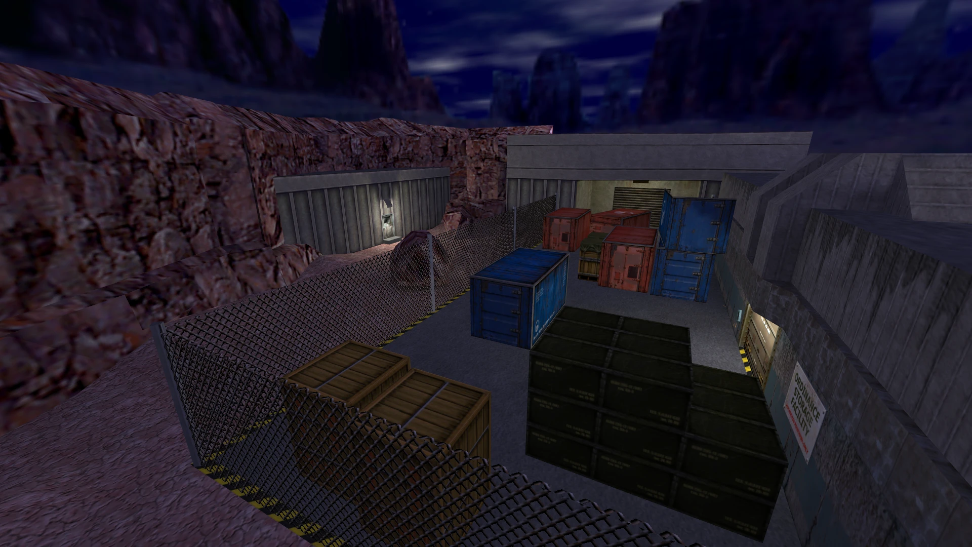 Área de almacenamiento vallada con cajas y contenedores fuera de un edificio de concreto por la noche en el mod de Half-Life