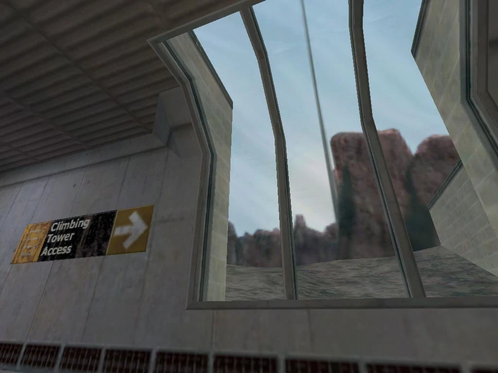 View of climbing tower access sign mounted on wall inside concrete base with barred window showing rocky landscape