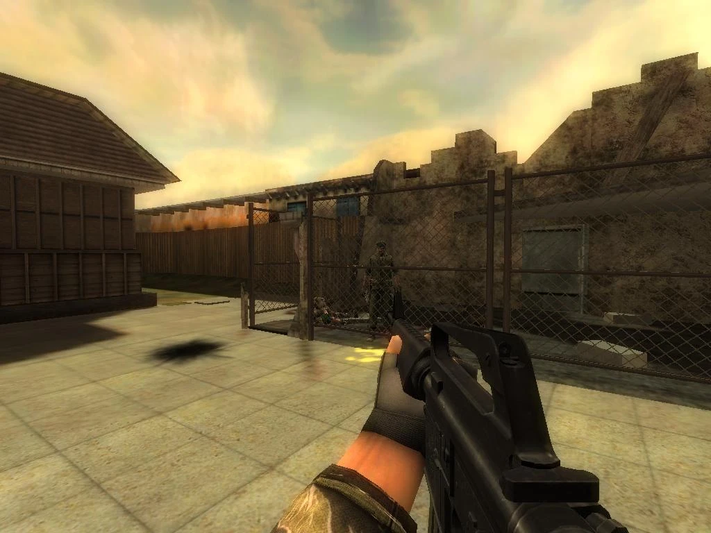 First-person view in Half-Life mod Heart Of Evil Napalm Edition showing weapon aimed at enemy behind fence