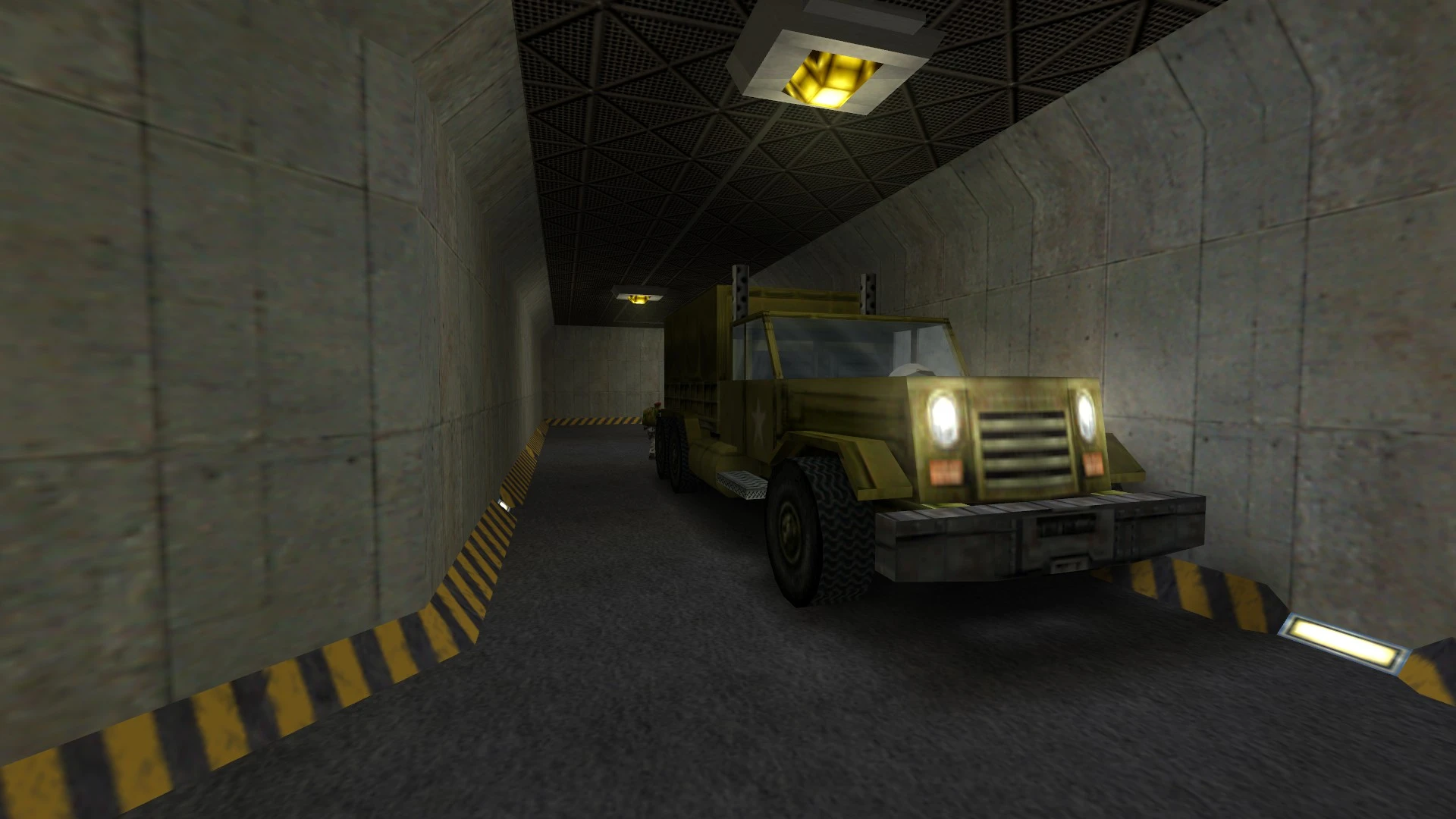 Screenshot of a military truck with headlights on inside a narrow concrete-walled underground tunnel lit by ceiling lamps