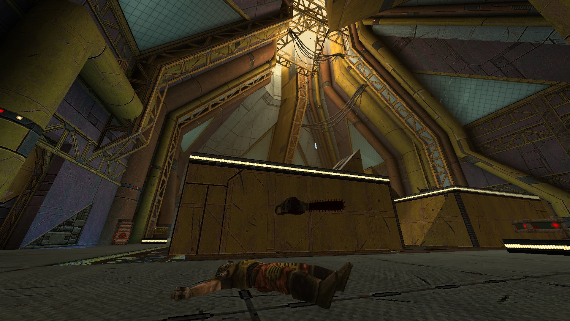 Vista de una gran sala industrial con tuberías amarillas y un personaje muerto en el suelo metálico en el mod Alkaline de Quake