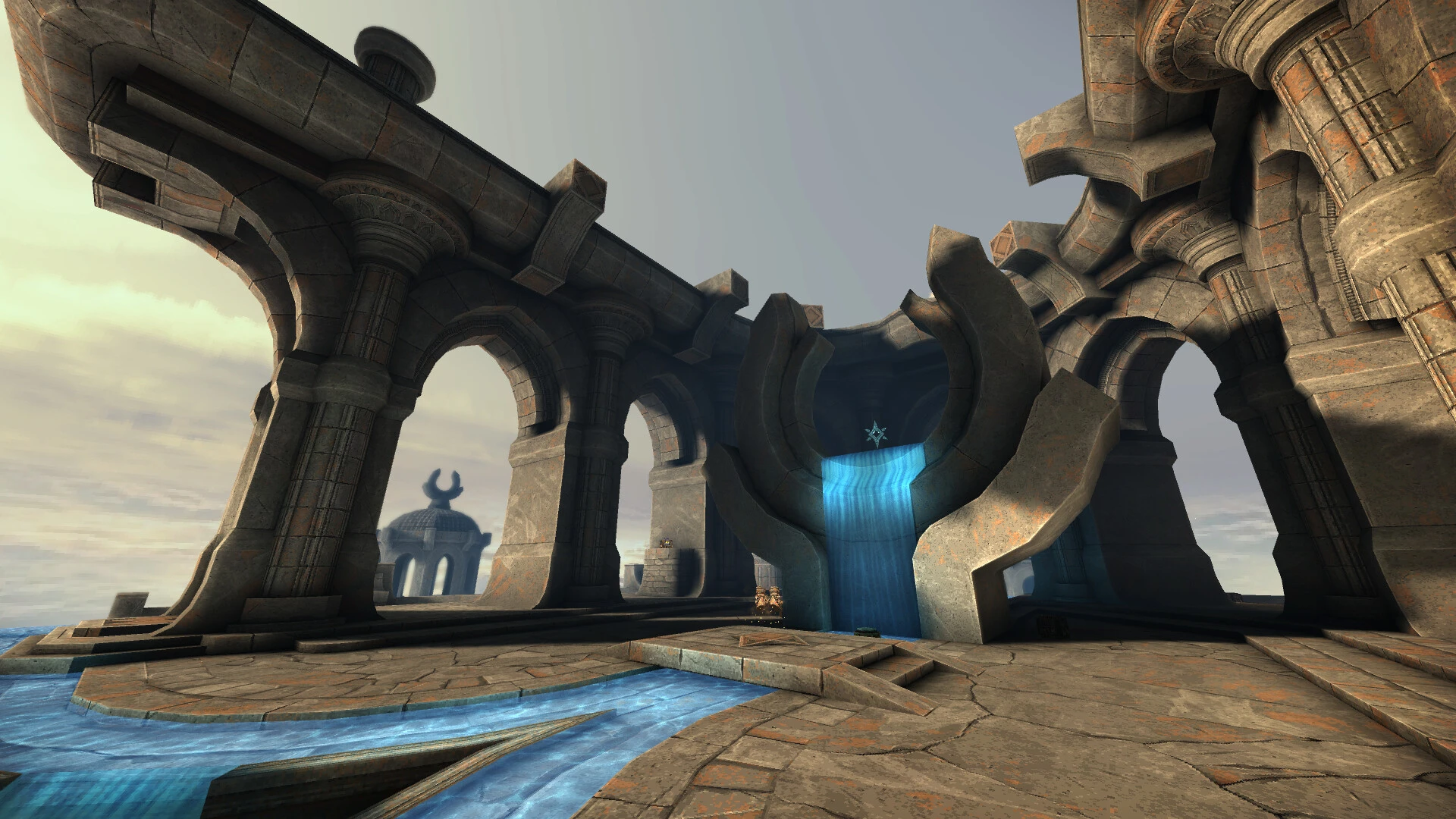 Widok z gry na okrągłą kamienną konstrukcję z łukami i niebieskimi wodospadami w modzie Quake Arcane Dimensions