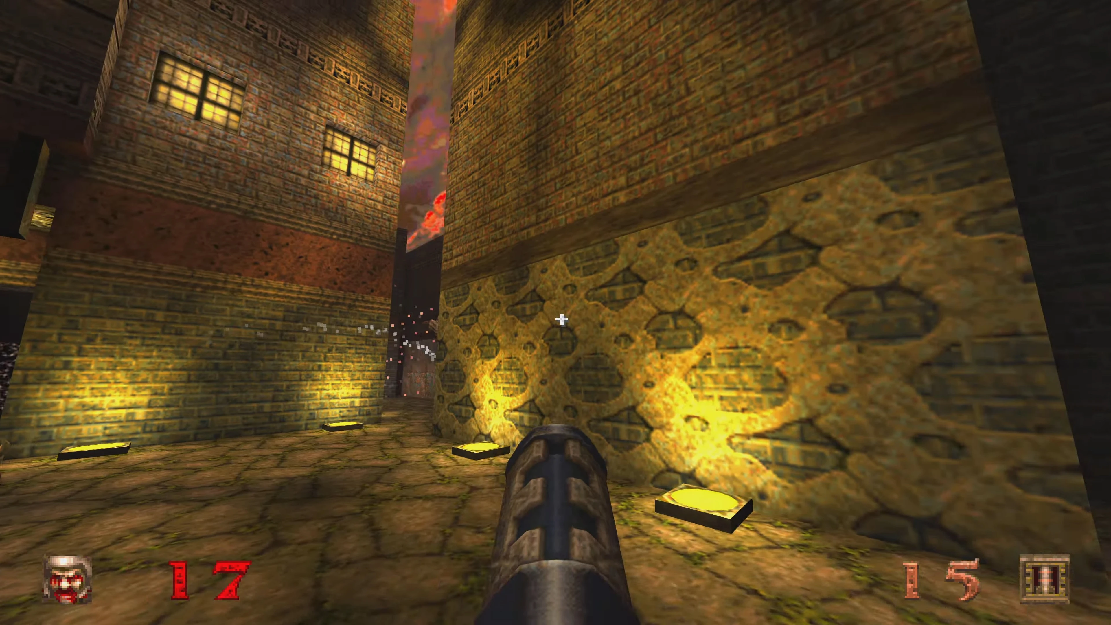 Widok z pierwszej osoby w modzie The Spiritworld do Quake 1996 pokazujący broń zwróconą na oświetlony żółtym światłem starożytny ceglany korytarz